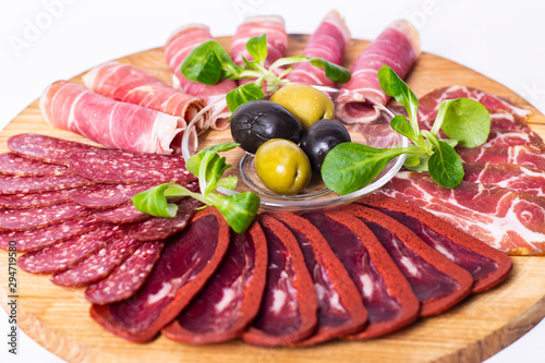 Food tray with delicious salami, pieces of sliced ham, sausage and olives. Meat platter.