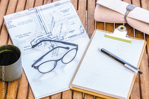 Bureau d'architecte ou ingénieur du bâtiment - bureau féminin en bois avec un plan de construction et fournitures  de bureau lunettes tasse à café stylo trousse  photo