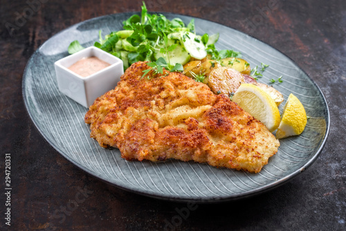 Deep fried Wiener schnitzel from veal topside with fried potatoes and lettuce as closeup modern design plate