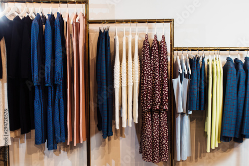 Close-up view of various stylish clothes hanging on hangers in boutique. Clothes
