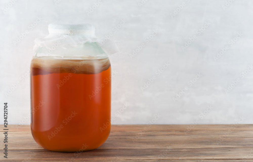 Kombucha tea mushroom in the glass jar on the wooden background. Kombucha tea mushroom in the glass jar on the wooden background.