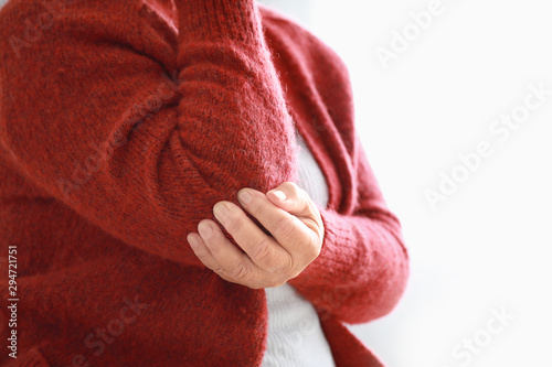 Senior woman suffering from pain in elbow at home, closeup