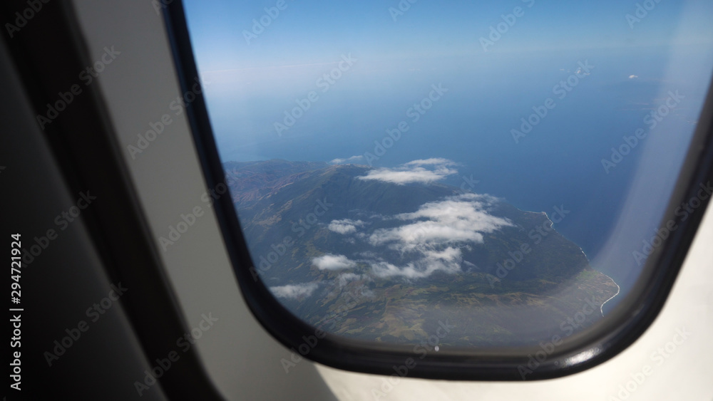 aircraft porthole window with blue sea or ocean in it and small tropical islands. Looking through window aircraft during flight aircraft porthole window with blue sea or ocean in it and small tropical islands. Looking through window aircraft during flight