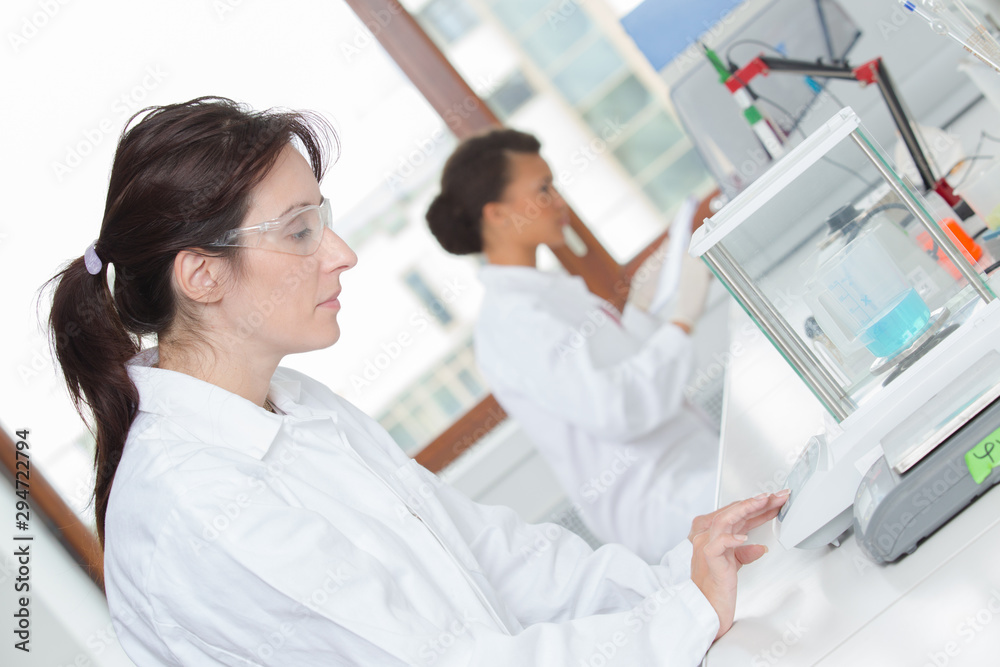 women working in laboratory using scales women working in laboratory using scales
