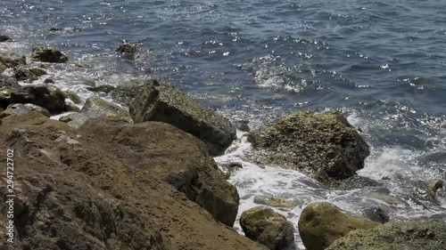 Close up shot of a blue waves of a beautiful sea crushing onto stones of a sea shore. photo