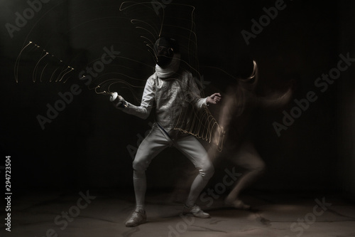 Fencer in white outfit is performing fight. Multi Exposure, freeze light, dark background 