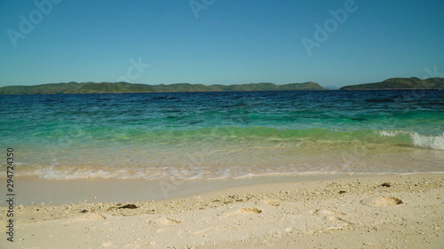 Sandy beach on the island and waves rolling on the coastline. Malajon Island, Philippines, Palawan. Summer and travel vacation concept.