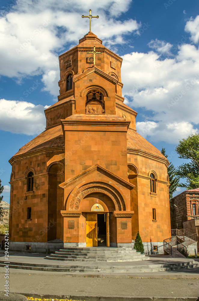  Facade with the entrance under the beautiful arched portal of the bell tower with a copper cross in the Catholic Cathedral of the Holy Martyrs in Gyumri
