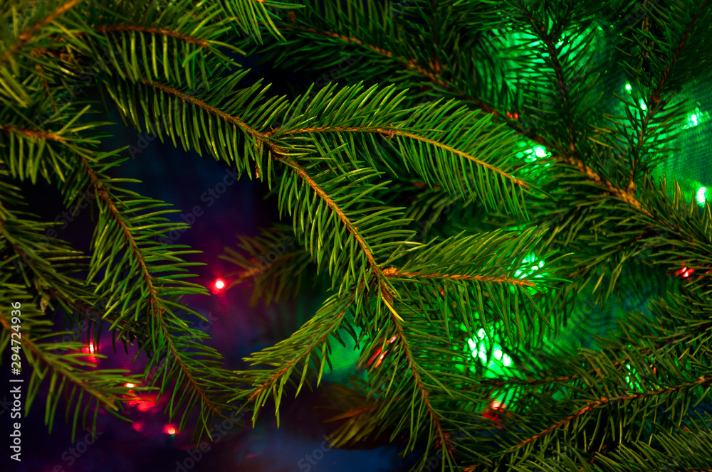 Christmas tree branches in bright lights.  New Year color background