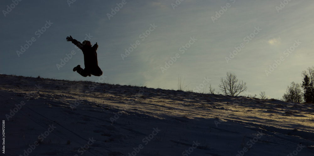 silhouette of a boy jumping in snow