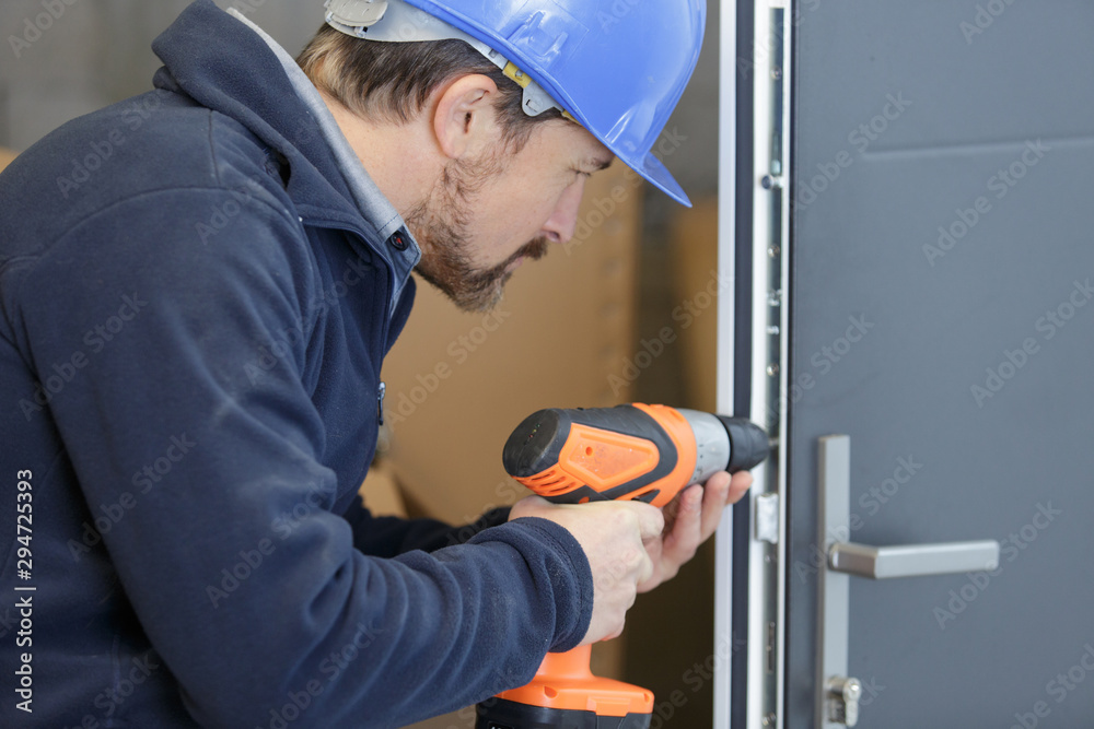 man drills a hole in a door man drills a hole in a door