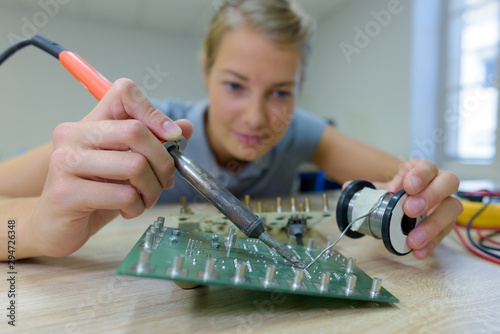 woman assembling works soldering iron