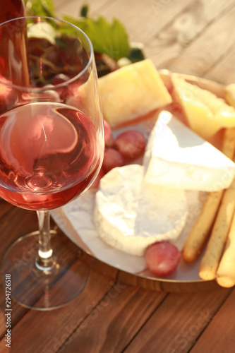 Glass of wine with snacks on wooden table
