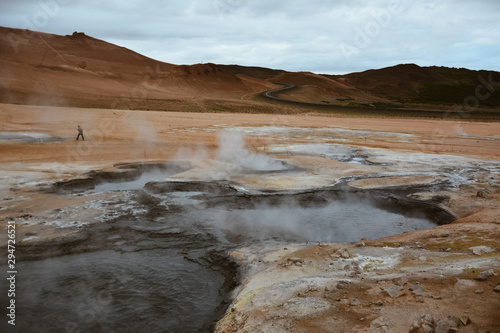 Boiling mudpots in the geothermal area Hverir and cracked ground around with unrecognisable tourists, Iceland in summer. Myvatn region, North part of Iceland