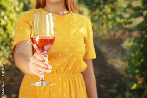 Young woman with glass of tasty wine in vineyard