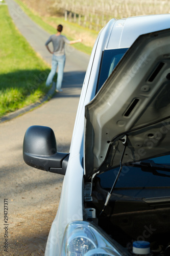 person thumbing a lift after car has broken down