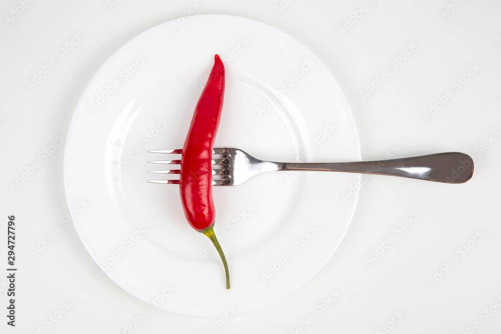 red hot pepper on a fork on a white plate. spices and vegetative food