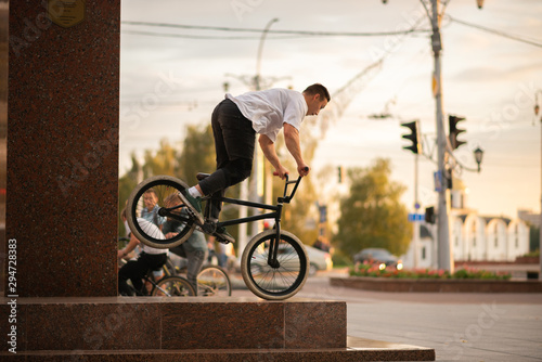 The guy stands on the front wheel of the BMX, on the parapet