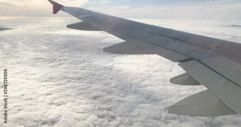 View of wing and engine of aeroplane from interior cabin through window over thick layer of cloud. Cloudscape from airline during morning journey. View of wing and engine of aeroplane from interior cabin through window over thick layer of cloud. Cloudscape from airline during morning journey.