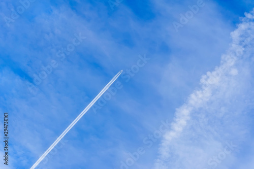 Airplane and trace, condensation trails, vapor trails. Bright blue sky background with diagonal jet plane trace