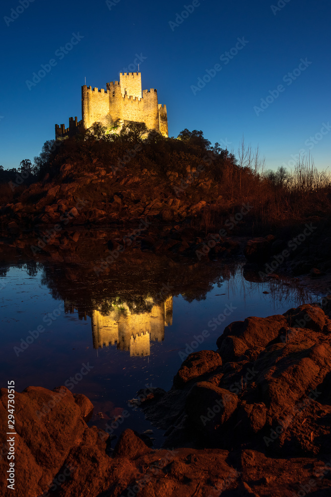 Almourol castle, in Portugal, at dusk with the reflection in the water of the Tagus river.