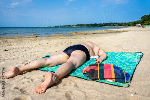 Mature plump woman sunbathing on the beach of the sea