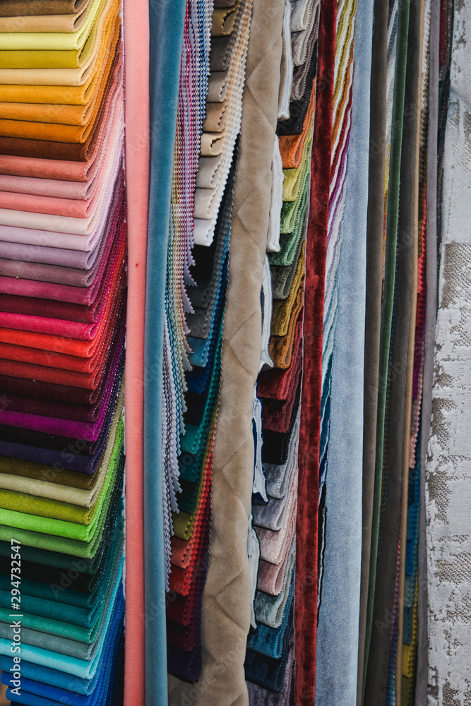 Many fabrics of different types. Colorful fabric swatches on shopfront. Textile samples background.