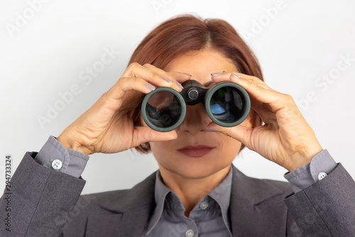 Business woman in suit looking through binoculars