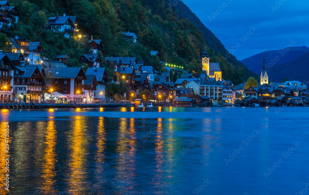 Sunset time at the famous village of Hallstatt capturing the iconic houses and church with a reflection on the lake. 