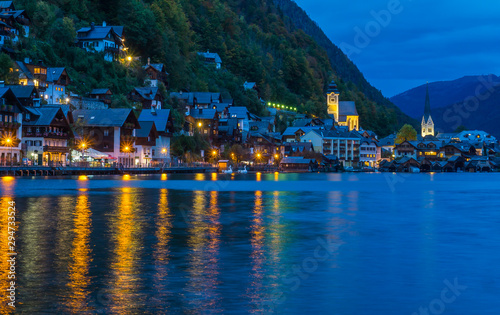 Sunset time at the famous village of Hallstatt capturing the iconic houses and church with a reflection on the lake. 