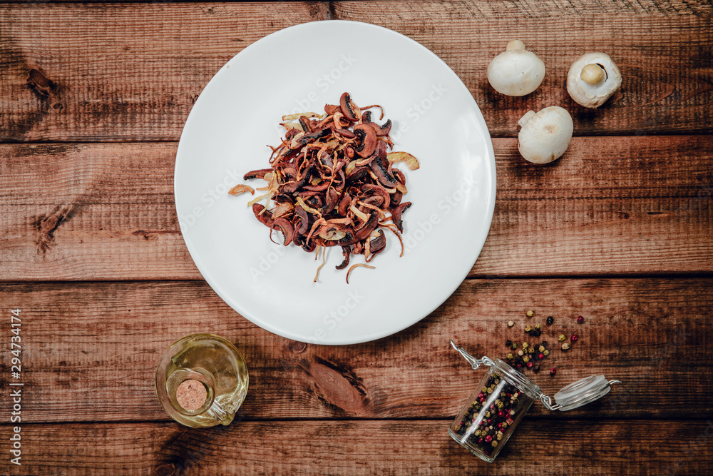 Fried Champignon on a wooden table. The concept of eating mushrooms, frying. Serving mushrooms with onions, side dishes. Tasty dishes. Fried Champignon on a wooden table. The concept of eating mushrooms, frying. Serving mushrooms with onions, side dishes. Tasty dishes.