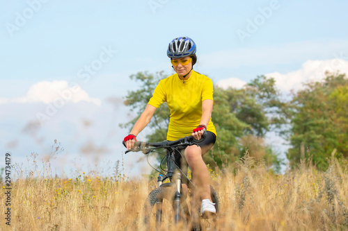 Beautiful girl cyclist rides on the field on a bicycle