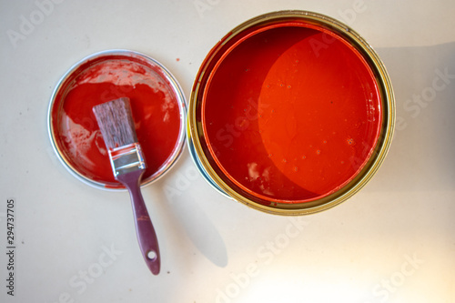 Paint brush on the can and red paint cans on the can placed