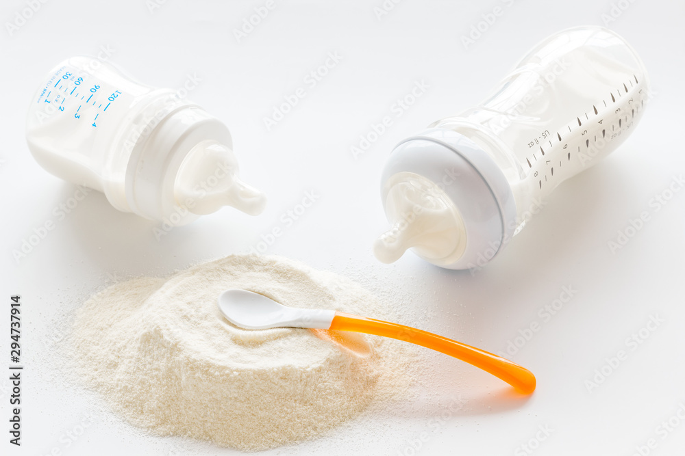 Baby food. Powder in spoon near baby bottle on white background Baby food. Powder in spoon near baby bottle on white background
