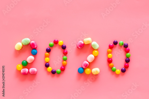 Sweet New Year design. 2020 laid out with candy on pink background top view copy space