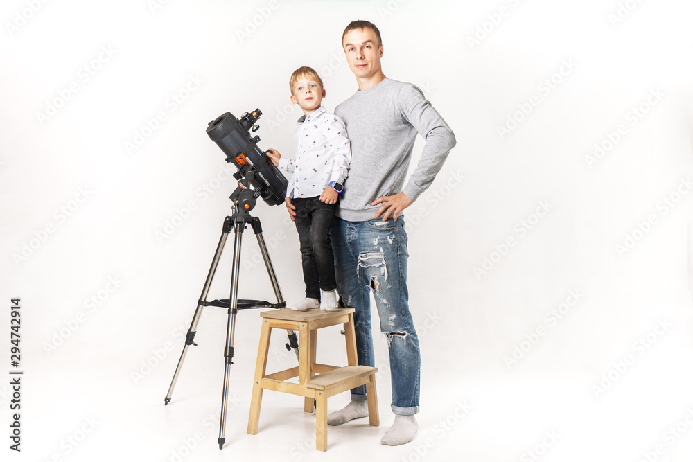 Father shows son how to use telescope.