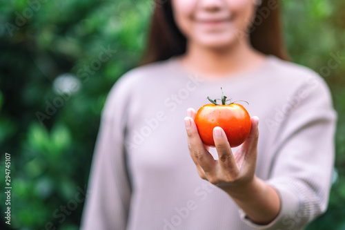 A woman holding a fresh tomato in hands