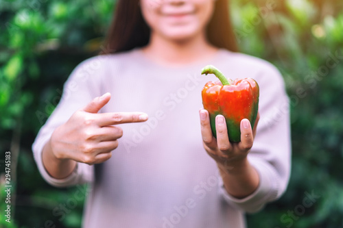 A woman holding and pointing finger at a fresh bell pepper