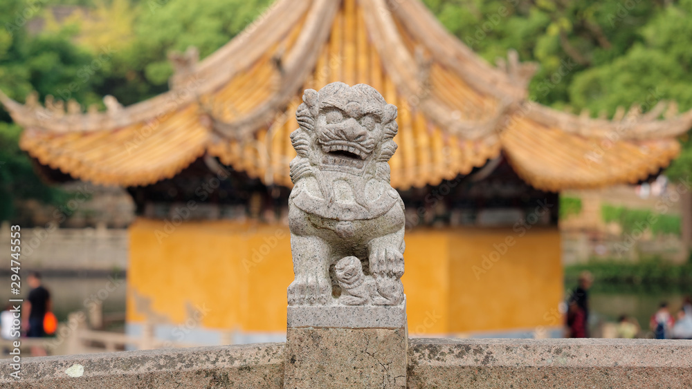 Beautiful carved stone Chinese lion with blurred temple background at Puji Temple in Putuoshan, Zhejiang province, China.