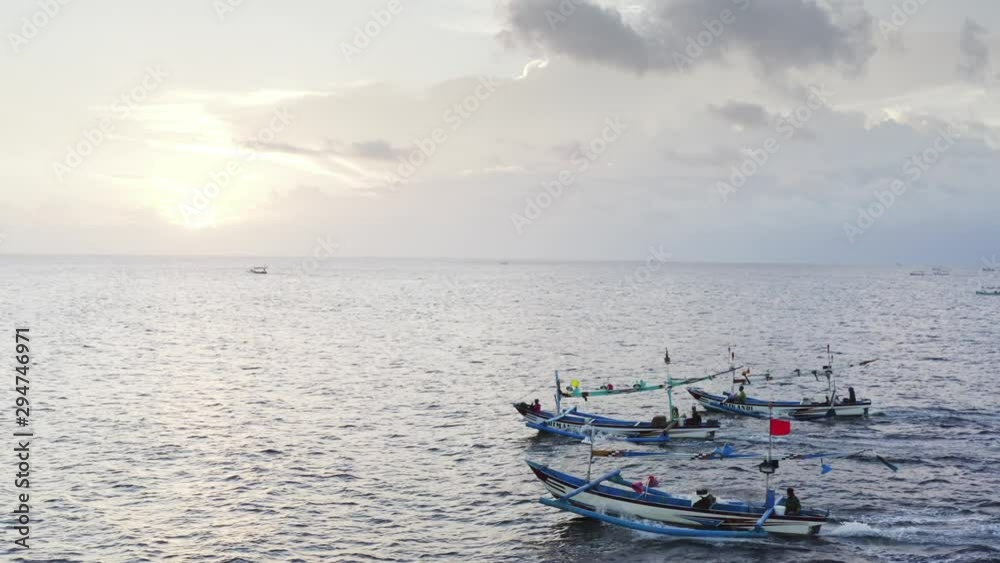 Aerial view of motor boats jukungs (traditional indonesian canoes) with fishermen sailing for night fishing in the ocean. Sunset. Bali, Indonesia Aerial view of motor boats jukungs (traditional indonesian canoes) with fishermen sailing for night fishing in the ocean. Sunset. Bali, Indonesia