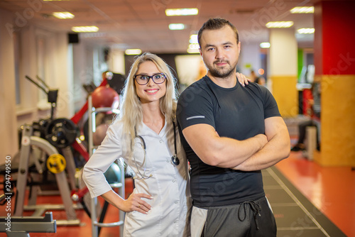 Female doctor and male patient at the gym. Sports Hall. Ambulance nurse. Sports doctor advises bodybuilder.