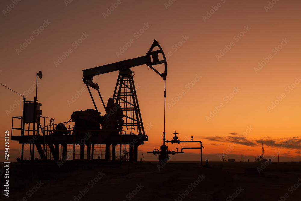 oil pumps at sunset,  industrial oil pumps equipment.