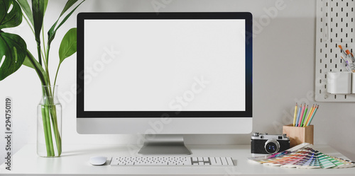 Modern designer workplace with blank screen desktop computer with camera and colour swatches