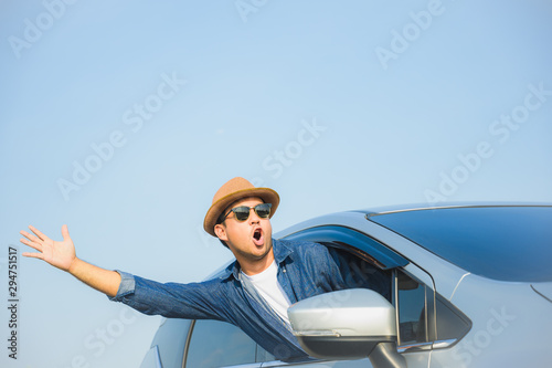 Young handsome asian man driving car to travel on his holiday vacation time with beautiful blue sky.
