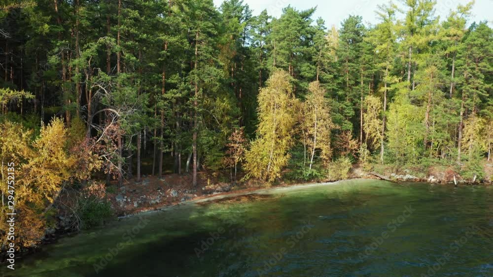 Aerial drone view of Turgoyak lake in autumn surrounded by Ural mountains, hills, mixed forest with green pines and yellow birchs; colorful trees on coasts; fragile ecosystem and anthropogenic impact Aerial drone view of Turgoyak lake in autumn surrounded by Ural mountains, hills, mixed forest with green pines and yellow birchs; colorful trees on coasts; fragile ecosystem and anthropogenic impact