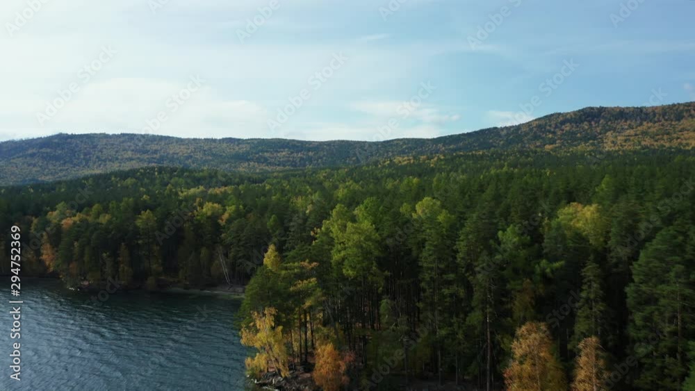 Aerial drone view of Turgoyak lake in autumn surrounded by Ural mountains, hills, mixed forest with green pines and yellow birchs; colorful trees on coasts; fragile ecosystem and anthropogenic impact Aerial drone view of Turgoyak lake in autumn surrounded by Ural mountains, hills, mixed forest with green pines and yellow birchs; colorful trees on coasts; fragile ecosystem and anthropogenic impact