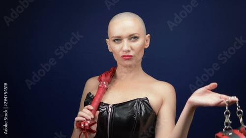 Very beautiful bald woman in a black leather corset with a whip and handcuffs on a dark background. copy space