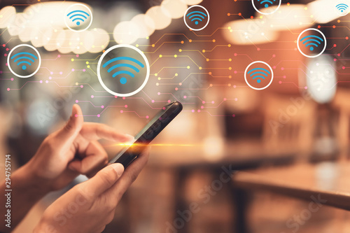 Woman hand using smart phone with wifi icon abstract background at coffee shop with colorful bokeh light. Technology business and modern lifestyle concept. photo