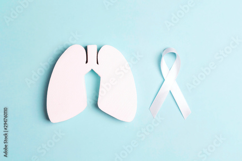 White lung cancer awareness ribbon and lung symbol on blue background. photo