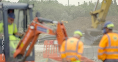 Large Industrial Crane and Workmen on Construction Site. Digger Lifting Quarry Earth in Britain.